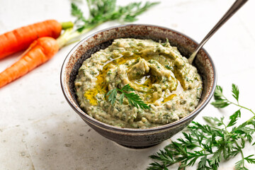 High angel view of bowl with a smooth and creamy dip made with carrot top and white mushed bean....
