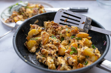 Fried potatoes with scrambled eggs, onions and chives in a frying pan