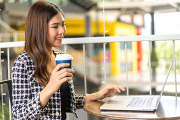 Portrait of smiling happy beautiful woman relax using technology of laptop computer sitting on chair.Young hipster creative girl freelancer business thinking with new idea content in cafe