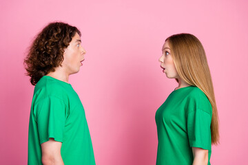 Side photo of two teeenagers look impressed each other when realized they wear accidentaly same t shirt isolated on pink color background - obrazy, fototapety, plakaty
