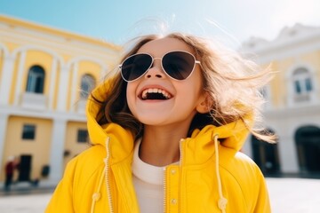 Portrait of a beautiful little girl in a yellow jacket and sunglasses