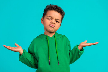 Photo of clueless gloomy schoolboy with wavy hair dressed green pullover palms demonstrate empty...