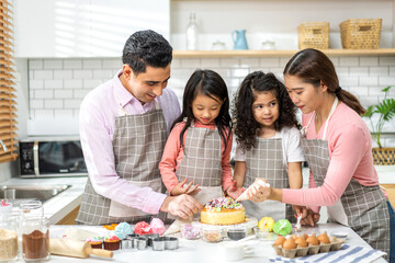 Obraz na płótnie Canvas Portrait of enjoy happy love asian family father and mother with little asian girl daughter child play and having fun cooking food together with baking cookie and cake ingredient in kitchen.