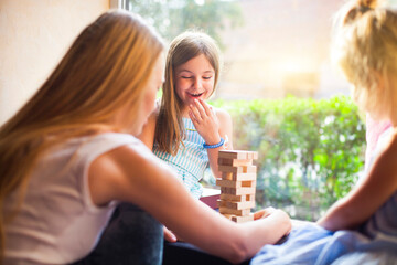 Happy mother with two children playing the wooden blocks tower