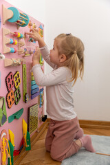 Toddler girl playing alone with the wooden toys
