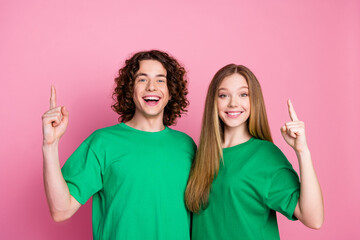 Photo of smiling happy curly haired teenage guy with girlfriend wear green t shirt direct fingers...