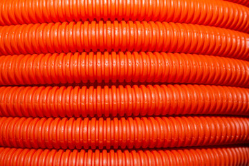 Stack of new orange polypropylene pipes. Close up.