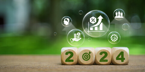 Implementation of the New Year goal plan 2024. Wooden cube with year 2024 and goal icons on green background. Business plan and development to achieve goals Target achievement. - obrazy, fototapety, plakaty