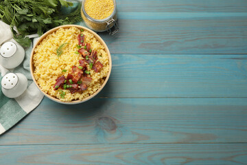 Tasty millet porridge with bacon, green onion and dill in bowl on light blue wooden table, flat lay. Space for text