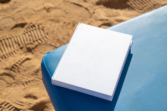 blank book mockup on lounge on sandy beach