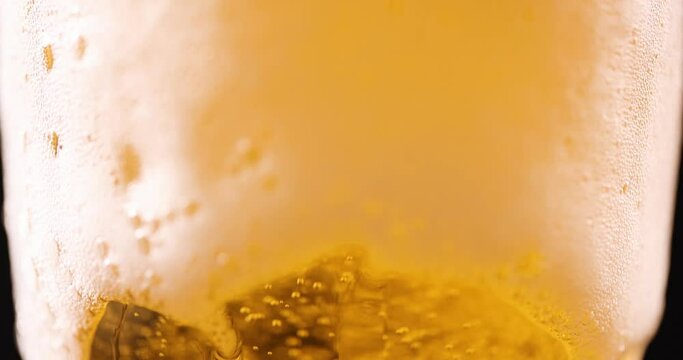 White foam flowing out of glass goblet with golden beer closeup 4k movie slow motion. Beer sale concept