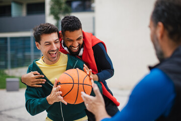 Best friends playing sport outdoors, having fun, competing. Playing basketball at a local court,...