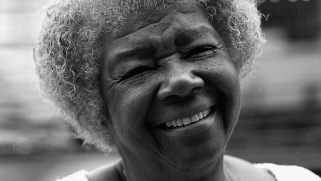 One joyful black senior woman portrait face smiling at camera. Friendly charismatic elderly lady in 80s with wrinkles and gray hair in monochromatic, black and white