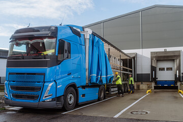 Warehouse receivers unloading of the truck in front of warehouse, checking delivered items.