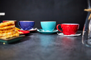 multicolored tea cups on the table against a black wall background