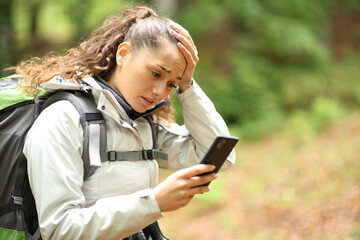 Lost hiker complaining checking cell phone in a forest