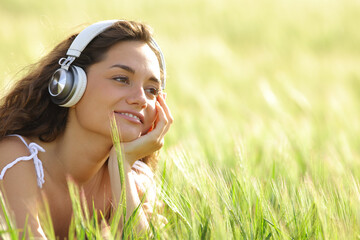 Relaxed woman listening music with headphones in a field