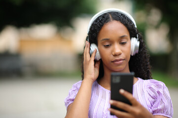 Serious black woman listening audio in the street