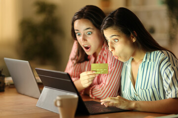 Two amazed tele workers buying online in the night - obrazy, fototapety, plakaty