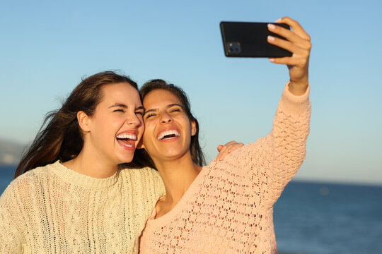 Two happy friends taking selfies on the beach
