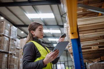 Female warehouse worker holding scanner, scanning the barcodes on products in warehouse. Warehouse...