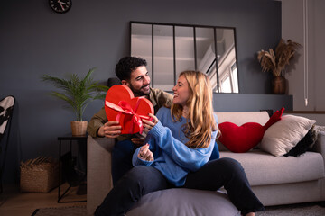 Beautiful young couple at home enjoying time together while celebrating Valentine's Day with a...