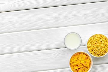 cereals, oatflakes and cornflakes with milk for healthy breakfast on white wooden background top view mock up