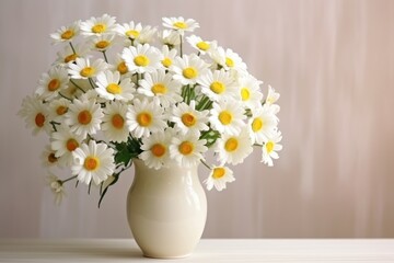  a white vase filled with lots of white and yellow daisies on top of a white table next to a wall.