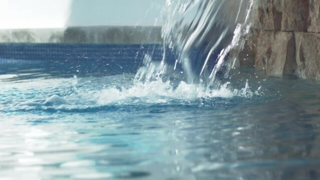 Artificial waterfall cascading over the water of a relaxing spa pool