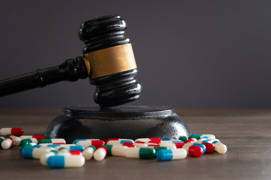 Closeup image of colorful medicine pills and judge gavel on table. Medical law concept.