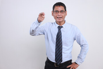 Angry Asian businessman wear glasses shouting and pointing finger at camera isolated over white background