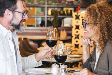 Happy couple smiling and talking in a burger pub restaurant - Married couple having lunch break at cafe bar - Lifestyle concept with man and a woman going out on weekend day