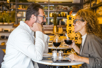 Happy couple smiling and talking in a burger pub restaurant - Married couple having lunch break at cafe bar - Lifestyle concept with man and a woman going out on weekend day