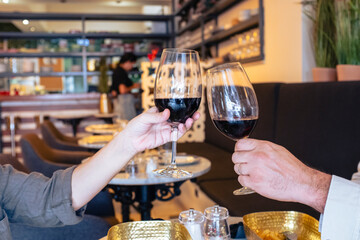 Beautiful wedding couple with glasses of red wine in pub restaurant toasting to celebrate. Free time concept