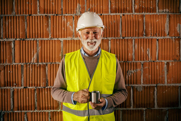 Portrait of a senior architect having coffee break while smiling at the camera.
