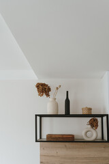 Modern minimal Scandinavian home interior with decorations. Shelf with caskets, vases and flowers