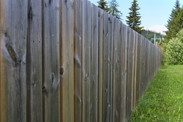 Solid wooden fence in the village in summer.