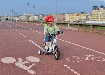 Girl in helmet learns riding a four-wheeled bicycle