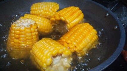 the process of cooking corn on the cob by soaking the corn in boiling water until cooked