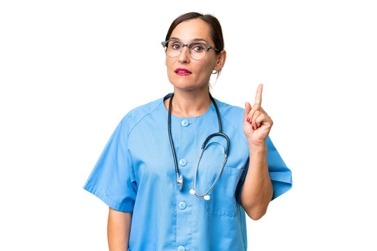 Middle-aged nurse woman over isolated background thinking an idea pointing the finger up