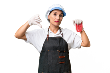 Butcher woman wearing an apron and serving fresh cut meat over isolated background showing thumb down with negative expression