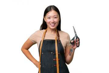 Young Asian seamstress woman over isolated background posing with arms at hip and smiling