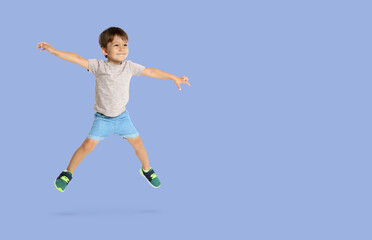 Fototapeta premium Happy boy jumping on light blue background, space for text