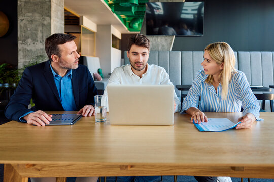 Business People Discussing Over Laptop And Graphs At Desk