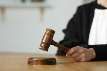 Judge striking mallet at wooden table in courtroom, closeup. Space for text