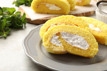 Delicious cake roll with cream filling on grey table, closeup