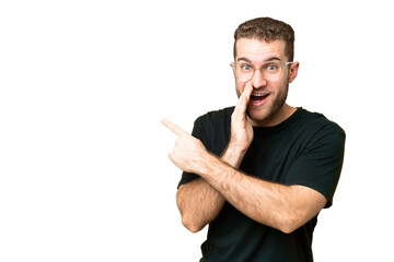 Young handsome blonde man over isolated chroma key background pointing to the side to present a product and whispering something