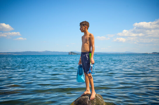 Teenage boy standing on rock in lake Bolsena, Italy