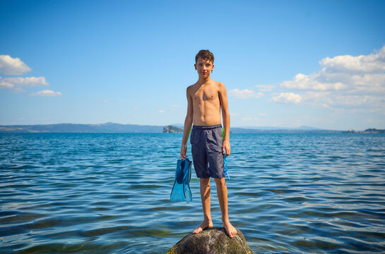 Boy standing on rock in lake Bolsena, Italy