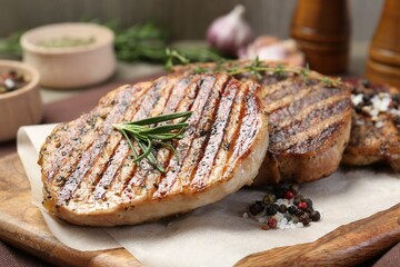 Delicious grilled pork steaks with herbs and spices on table, closeup